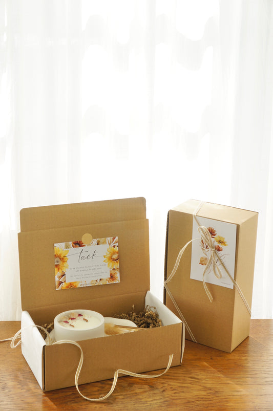 Presentbox med Botaniskt doftljus, ljusfat med gyllen dekor och en vektång. Produkterna ligger i en låda av naturfärgd papp. 