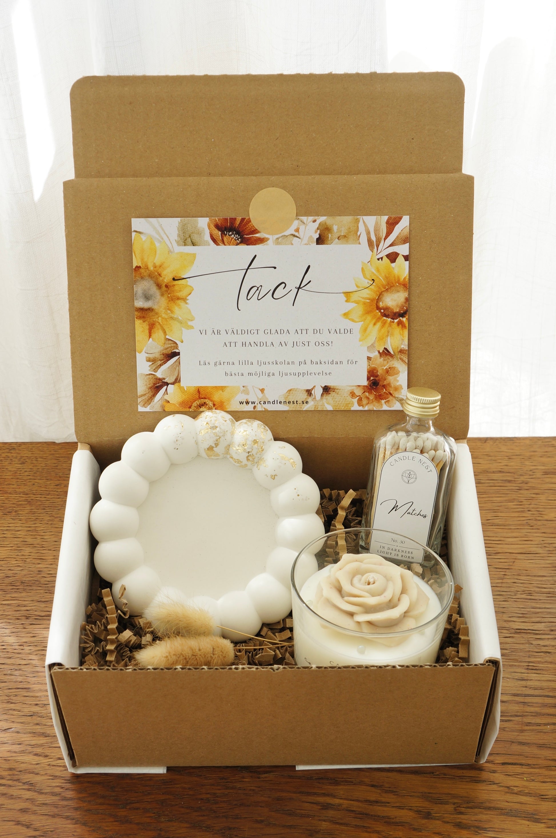 Lyxig Presentbox med ljusfat, Booms & Bubbles doftljus (Spiced rose latte), flaska med tändstickor. Bild snett ovanifrån.