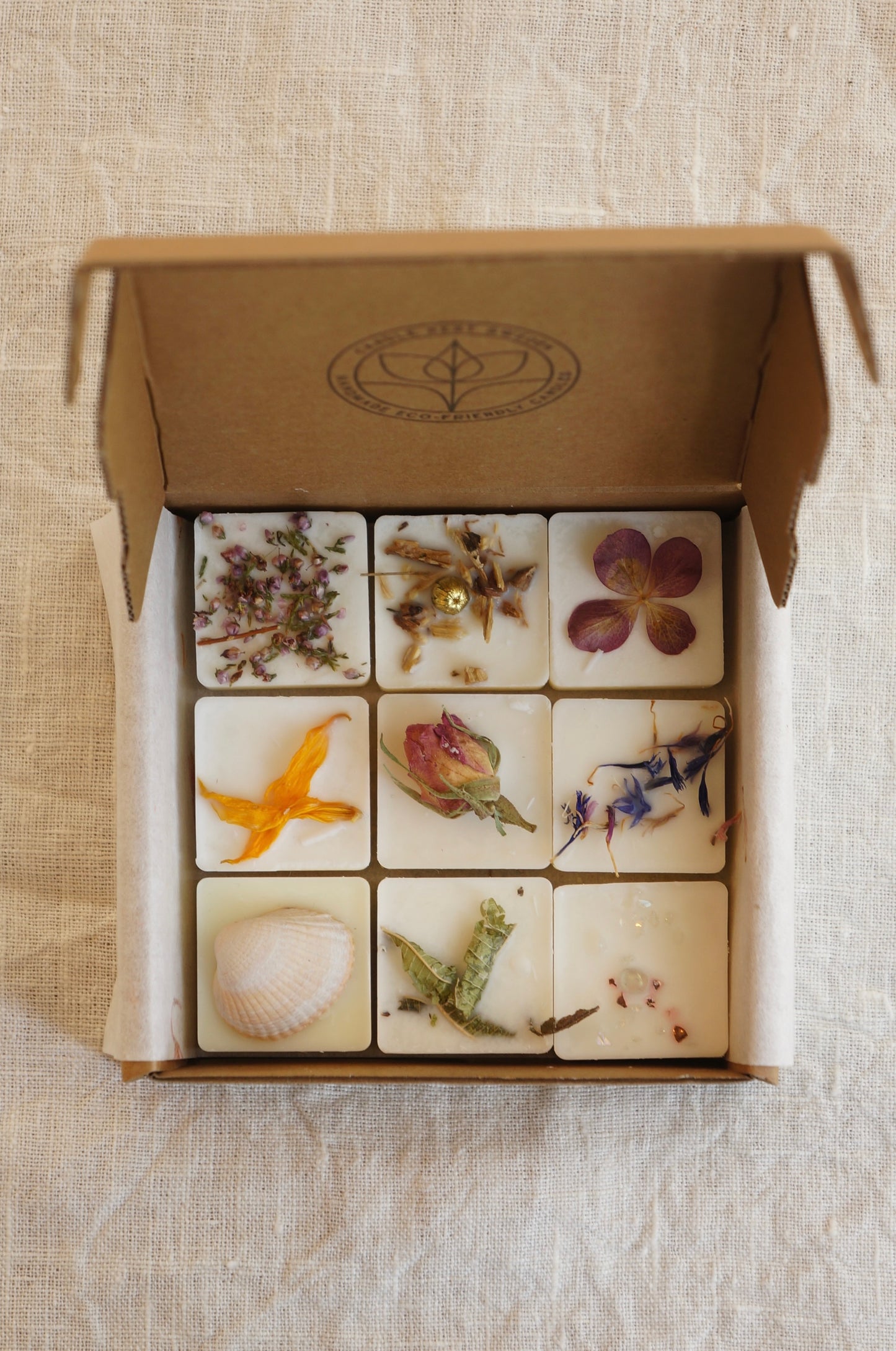 Doftpraliner eller även kallade doftvax. 9 stycken i kollektionen ”Mood Collection” i en vit ask. Pralinerna är dekorerade med torkade blommor. Bild tagen ovanifrån. 