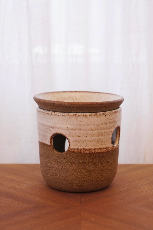 Produktbild av vit/grå aromalampa i keramik med värmeljus tänt under skålen, som sprider doft i rummet