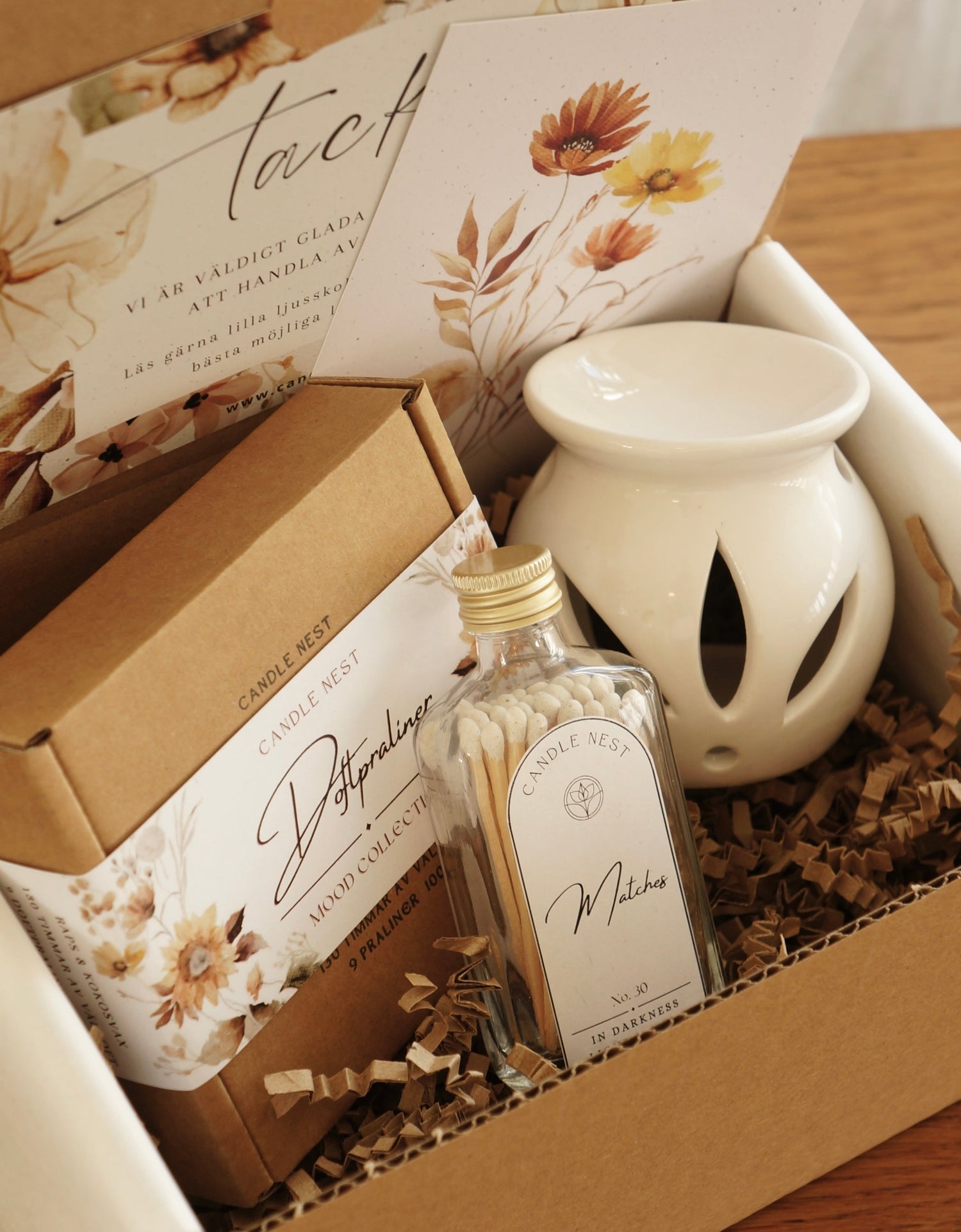 Kartong innehållandes en ask med doftpraliner, en flaska med tändstickor och en aromalampa